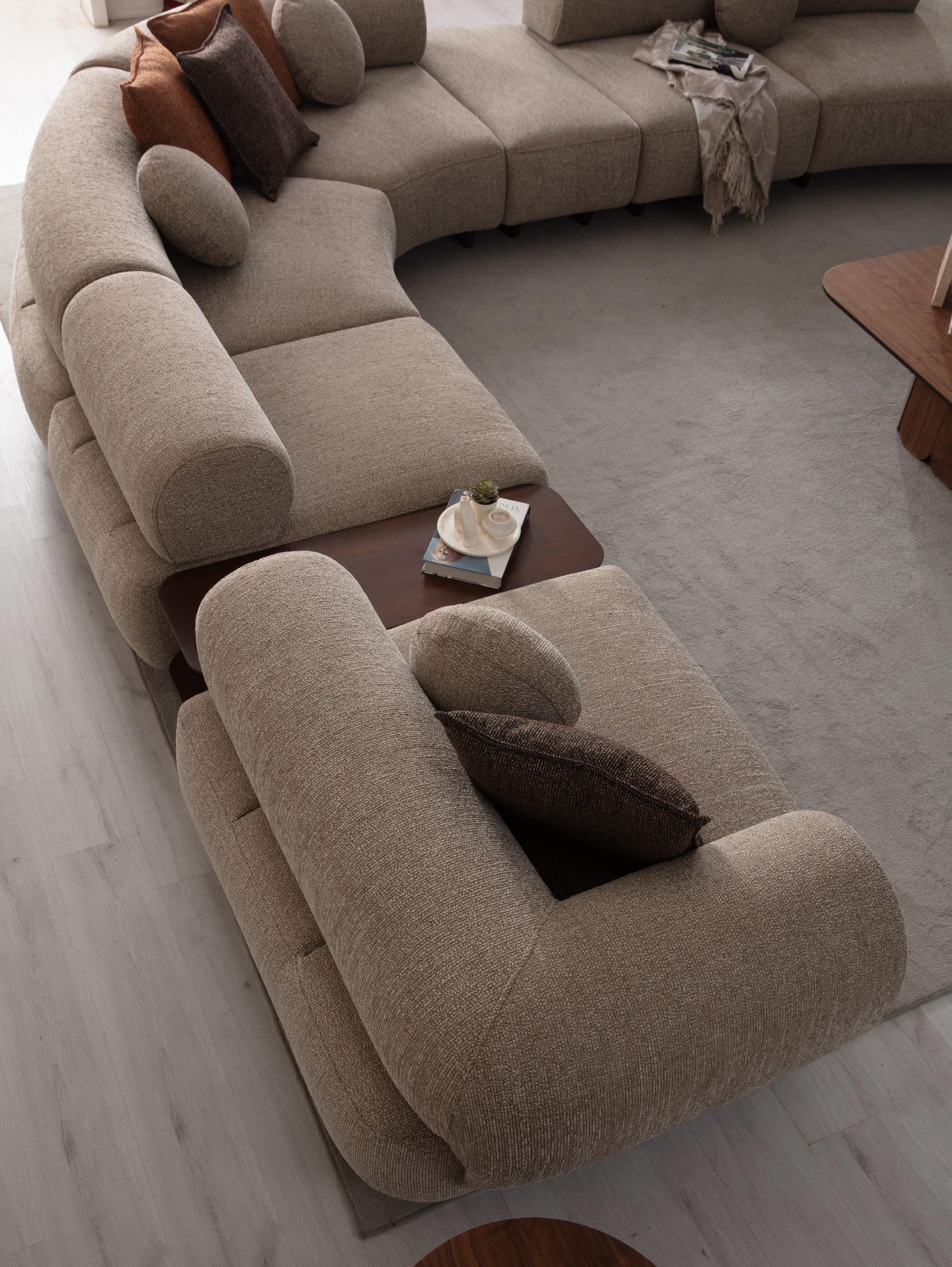 Canapea de living Aura cu formă curbată și perne decorative, integrată într-un decor minimalist.